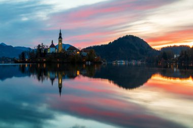 Slovenya 'daki Tiran Ulusal Parkı' ndaki Julian Alpleri 'ndeki şatonun arka planına karşı Bled Gölü' nün sıcacık gündoğumu