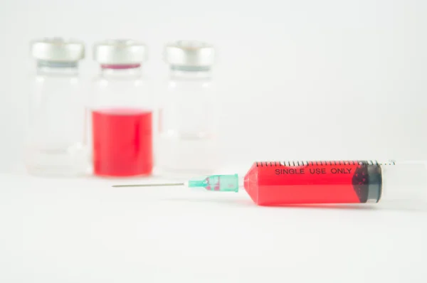 Červená kapalina v injekční stříkačky a lahvičky — Stock fotografie
