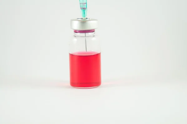 Disposable syringe and red liquid in injection vial — Stock Photo, Image