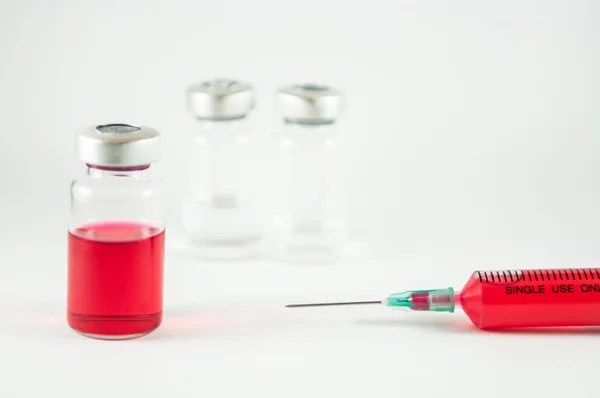 Röd vätska i injektionsspruta och flaskor — Stockfoto