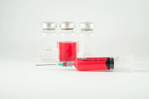 Líquido vermelho no frasco para injetáveis e seringa mostram conceito de medicamento — Fotografia de Stock