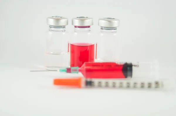 Disposable syringe and red liquid in injection vial — Stock Photo, Image