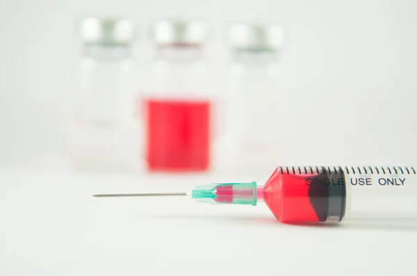Líquido vermelho em seringa para injectáveis e frasco para injectáveis fundo — Fotografia de Stock