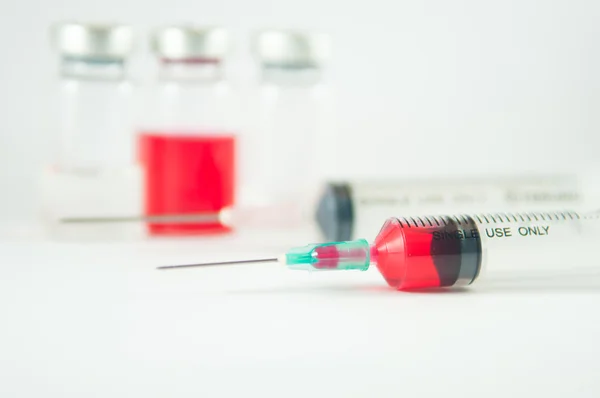 Red liquid in injection syringe and vials background — Stock Photo, Image