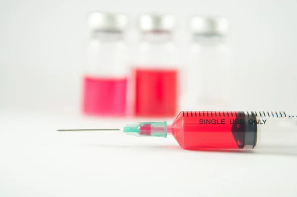 Líquido vermelho em seringa para injectáveis e frasco para injectáveis fundo — Fotografia de Stock