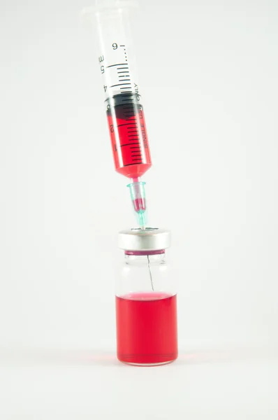 Red liquid in injection syringe and vials background — Stock Photo, Image