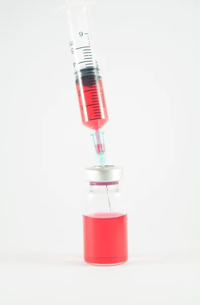 Red liquid in injection syringe and vials background — Stock Photo, Image