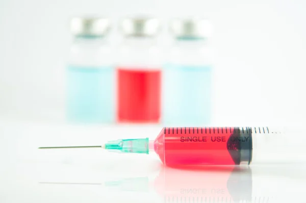 Röd vätska i injektionsspruta och flaskor — Stockfoto