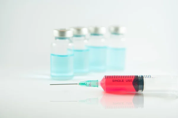 Red liquid in injection syringe and vials background — Stock Photo, Image