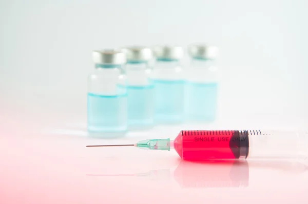 Red liquid in injection syringe and vials background — Stock Photo, Image