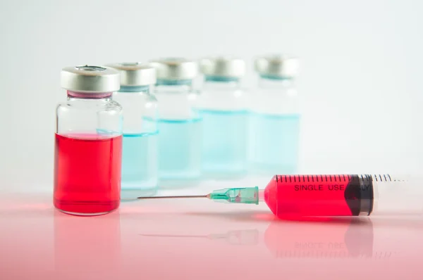 Rode vloeistof in injectiespuit en flesjes — Stockfoto