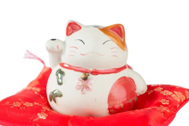 Kırmızı yastık üzerinde Maneki Neko kedi