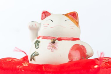 Kırmızı yastık üzerinde Maneki Neko kedi