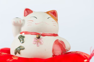 Kırmızı yastık üzerinde Maneki Neko kedi