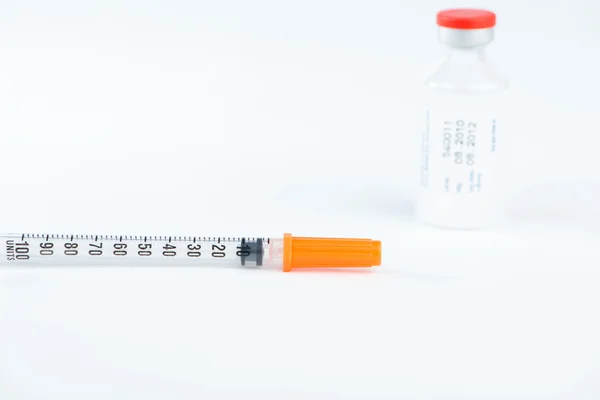 Closed up disposable syringe and red cap of injection vial — Stock Photo, Image