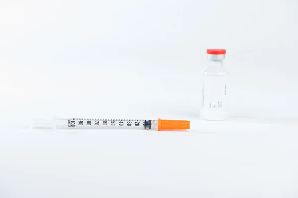 Closed up disposable syringe and red cap of injection vial — Stock Photo, Image