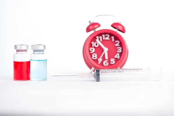 Red alarm clock and injection vials background show medicine and — Stock Photo, Image