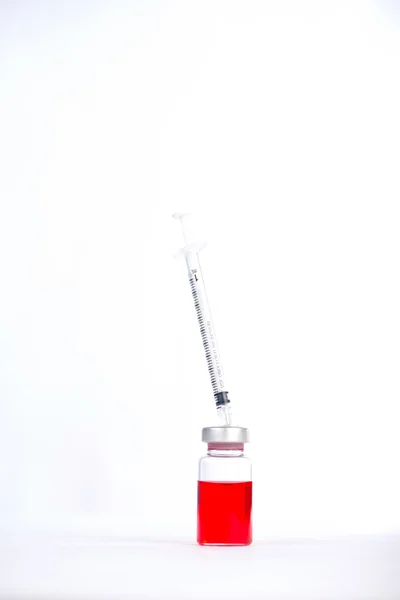 Seringue d'action placée sur du caoutchouc sur des flacons injectables — Photo