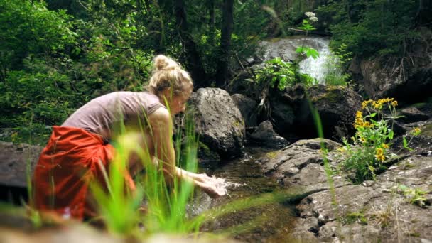 Женщина моет руки в ручье — стоковое видео