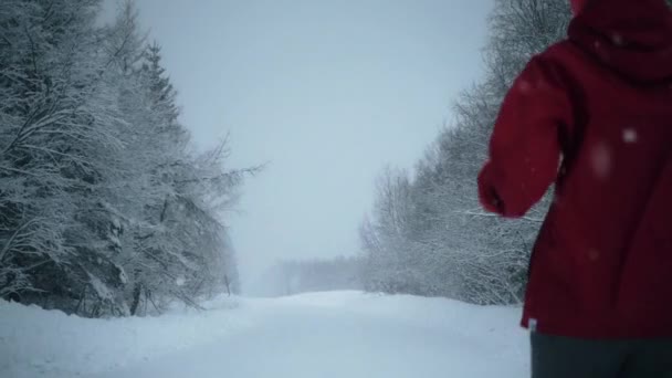 Blick auf Frau, die auf leerer, verschneiter Straße läuft — Stockvideo