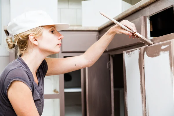 Großaufnahme einer Frau, die Küchenschränke bemalt — Stockfoto