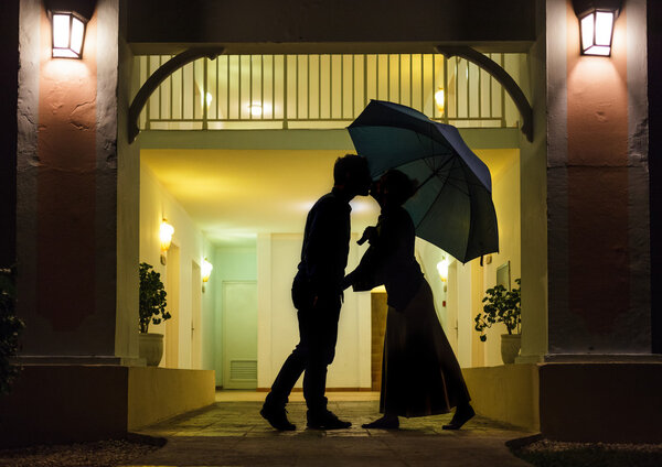 Couple in silhouette Kissing Under Umbrella