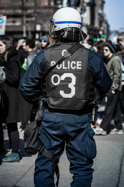 Detalle de la espalda de una policía frente a manifestantes . — Foto de Stock