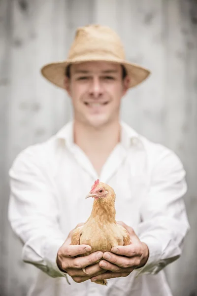 Agricultor segurando uma galinha bege — Fotografia de Stock