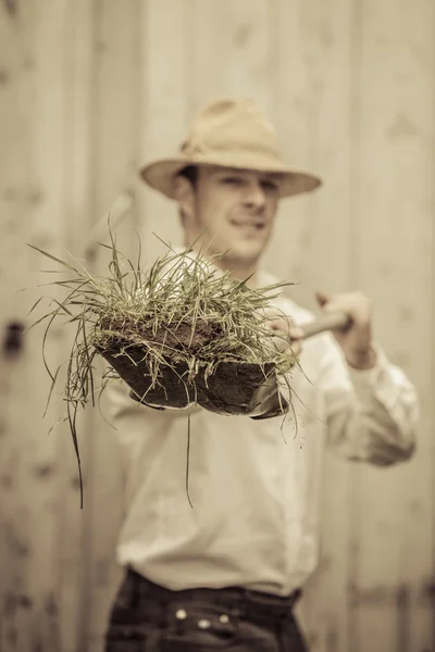 Bir kürek ile çiftçi çim dolu — Stok fotoğraf