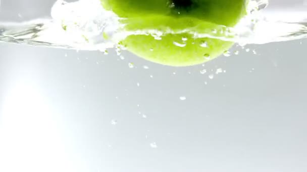 Manzana verde de cámara lenta estupenda de 180fps que cae en agua clara — Vídeos de Stock