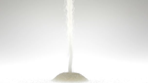 Super slow motion rå och naturligt socker som faller på vit bakgrund — Stockvideo