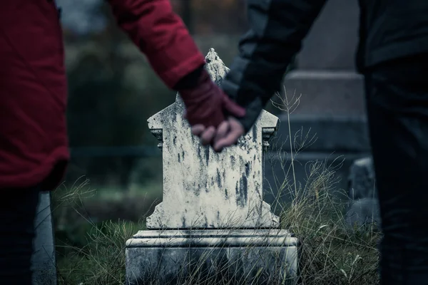 Hermano y hermana sosteniendo las manos frente a la lápida — Foto de Stock