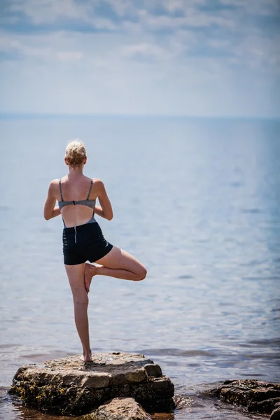 Vrouw doet Yoga boom positie — Stockfoto