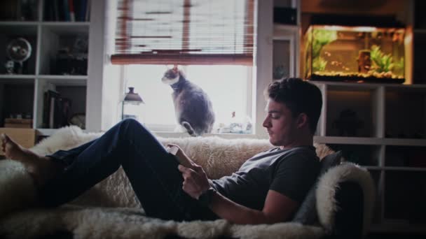 Homem lendo um livro no sofá — Vídeo de Stock
