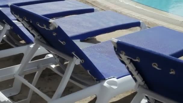 Bir resort havuz çevresinde güneşlenme koltukları — Stok video