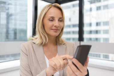 Orta yaşlı işkadını Smartphone kullanarak