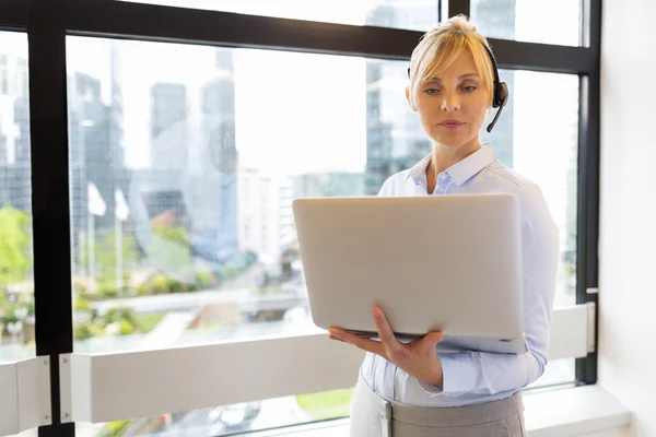 Atraktivní podnikání žena pracující na notebooku. Sluchátka. Budova b — Stock fotografie