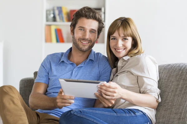 Retrato de pareja joven navegando por Internet con tablet PC en el sofá en casa —  Fotos de Stock