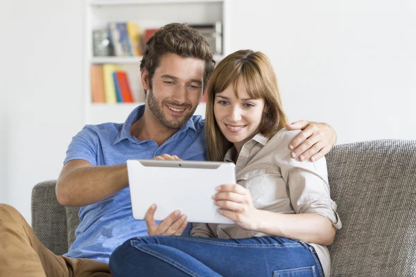 Ungt par surfa på internet tablet PC på soffan hemma — Stockfoto