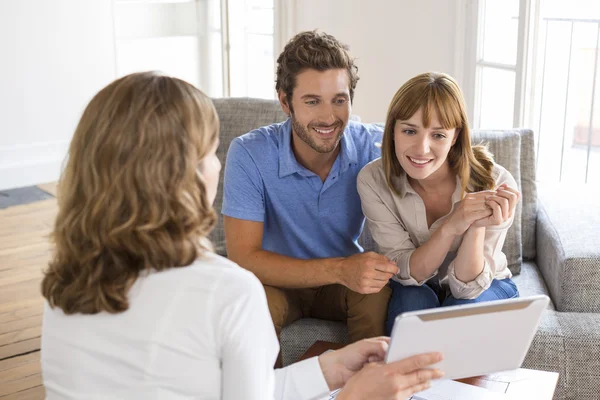 Arquiteto apresentando um novo projeto em tablet digital para um casal — Fotografia de Stock