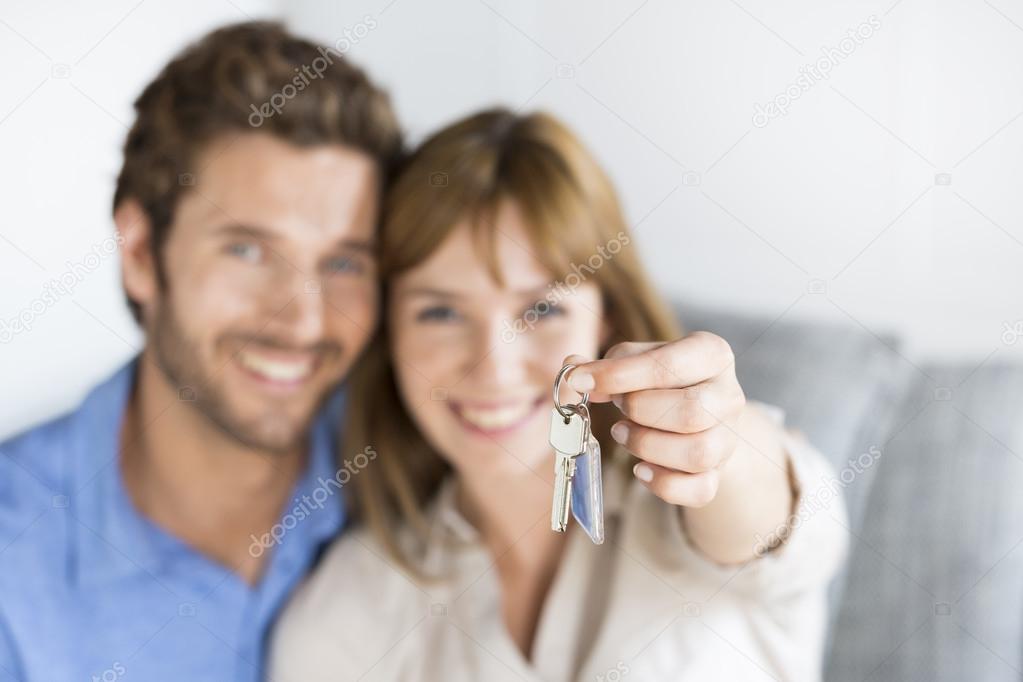 Cheerful thirty year old  couple showing a keys of their new apa