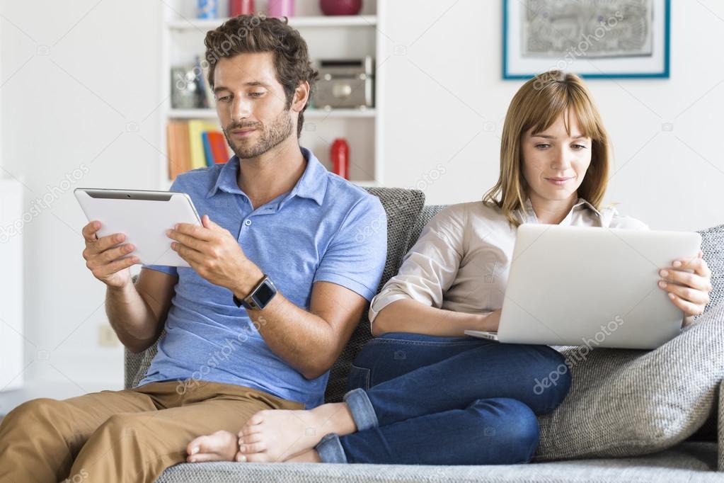 Digital geek couple on sofa at home