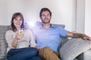Çift kanepede bir video projektör ile bir film izlerken