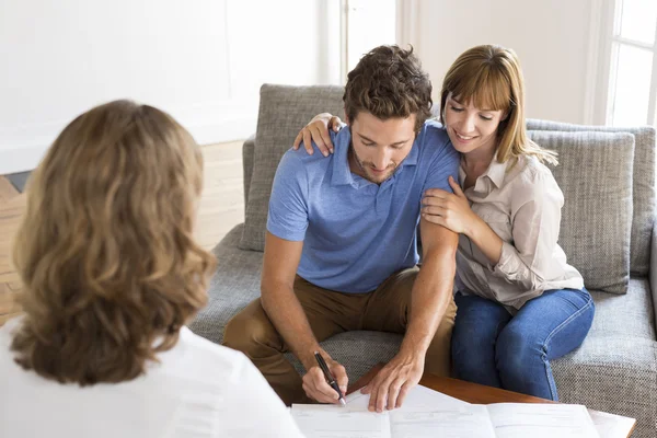 Propriétaires de jeunes couples signant un contrat avec un agent immobilier pour l'achat d'une maison — Photo