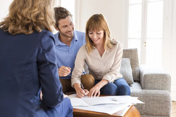 Propriétaires de jeunes couples signant un contrat avec un agent immobilier pour l'achat d'une maison — Photo