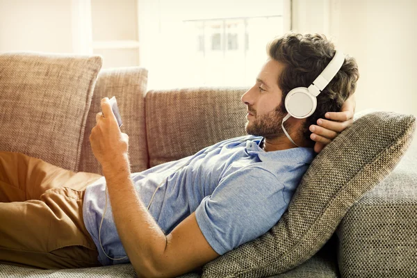 Man on couch watches a movie on mobile phone — Stock Photo, Image