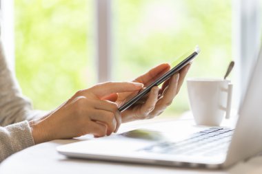 cep telefonu ve dizüstü bilgisayar kullanan kadın