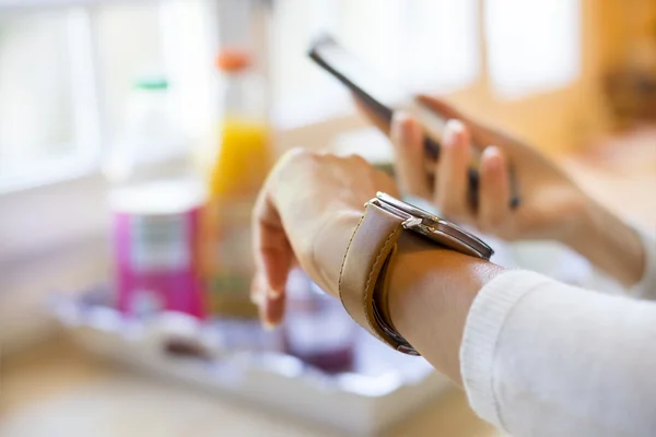 Vrouw met cellphone verbonden met een smartwatch — Stockfoto