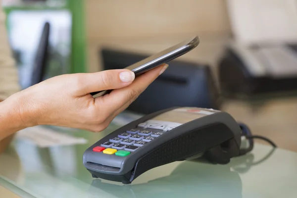 Mujer pagando con tecnología NFC en smartphone — Foto de Stock