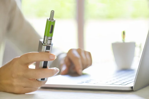 Женщина с электронными сигаретами и ноутбуком — стоковое фото
